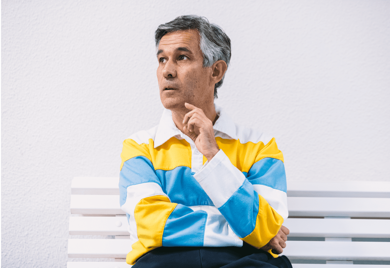 Adulto sentado en un banco pensativo