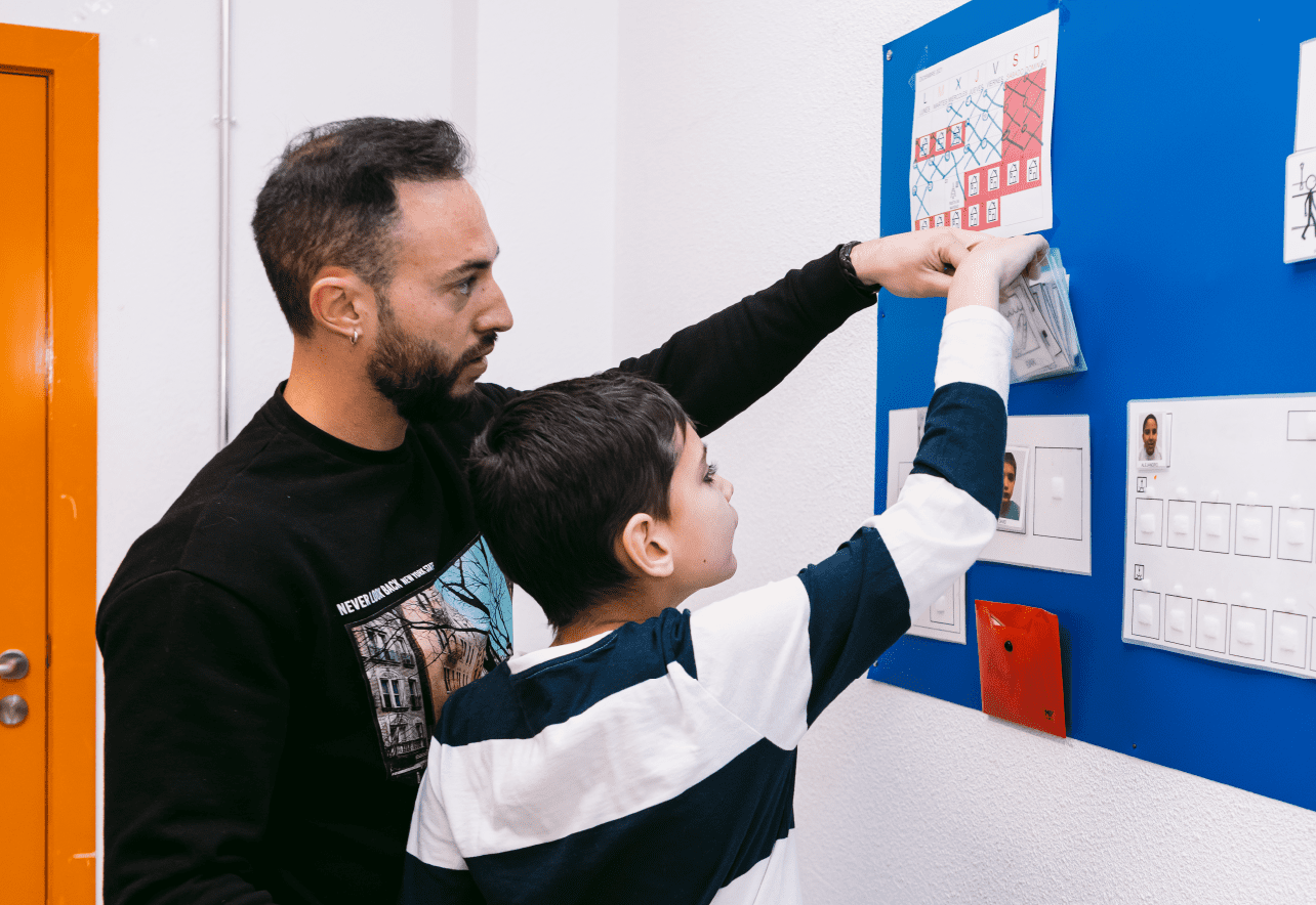 Niño y profesional tocando un tablero de pictogramas