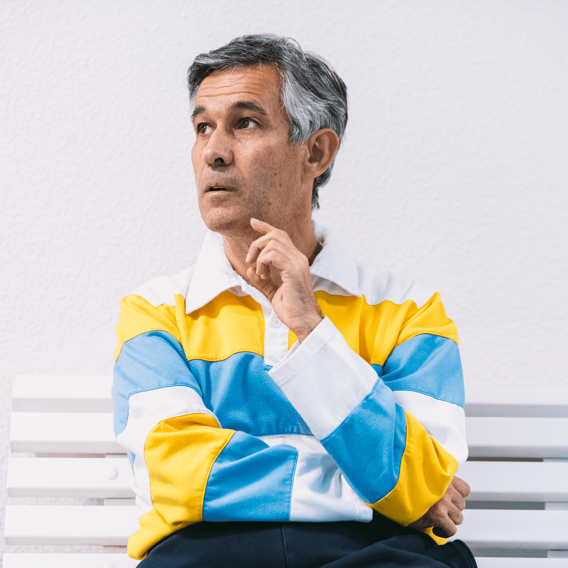 Un hombre con gesto pensativo sentado en un banco