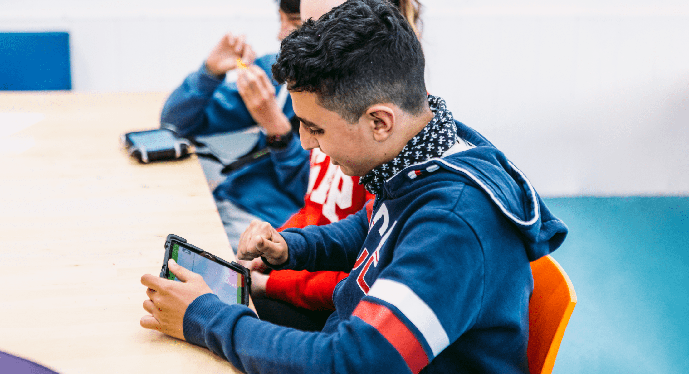Chicos sentados en su pupitre trabajando con tablets