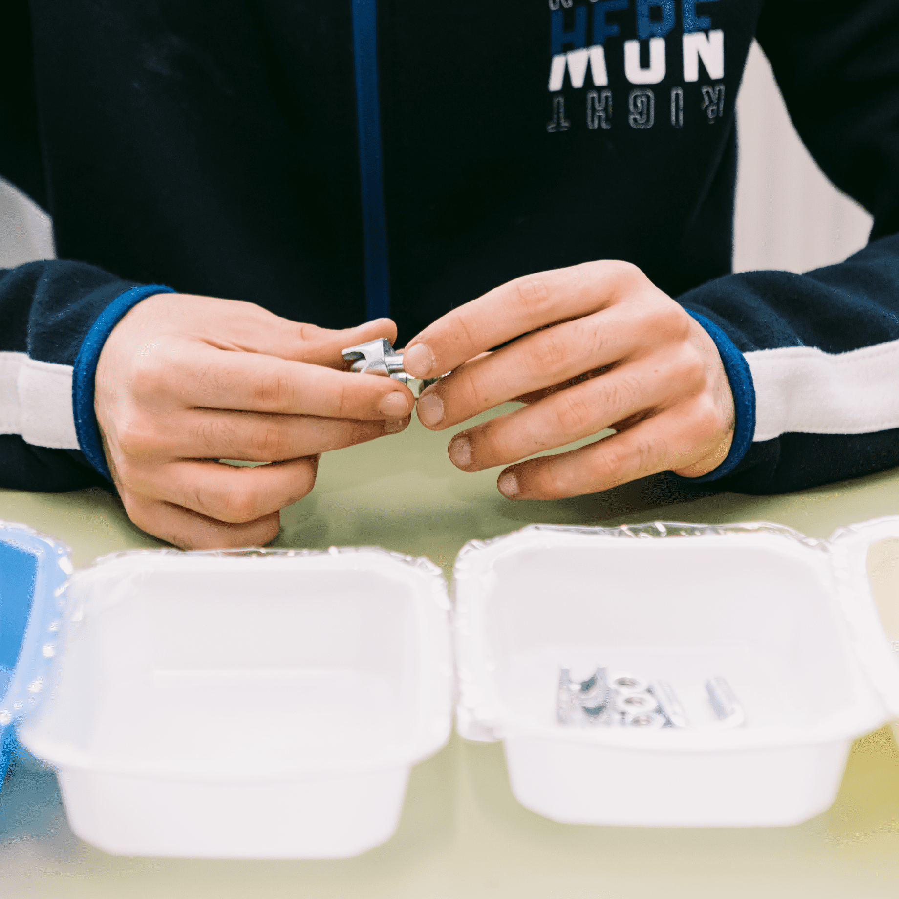 Dos manos trabajando con tornillos, tuercas etc.