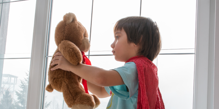 Miniatura de un niño de perfil sujetando un oso de peluche