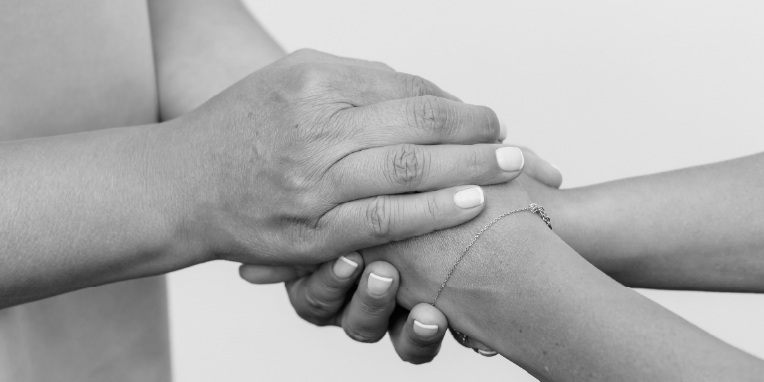 Dos manos sujetando las manos de otra persona