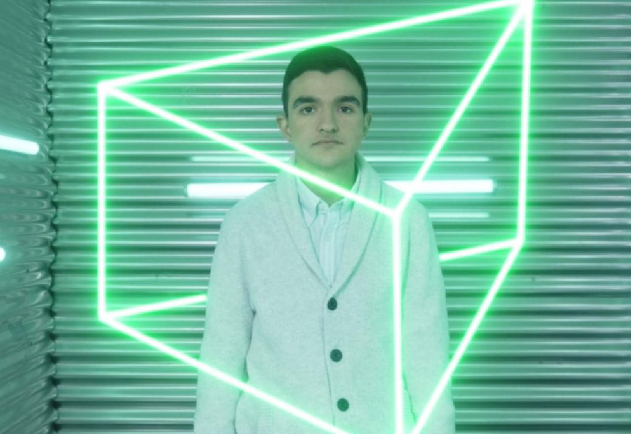 Niño mirando a cámara enfrente de un fondo con luces de neón