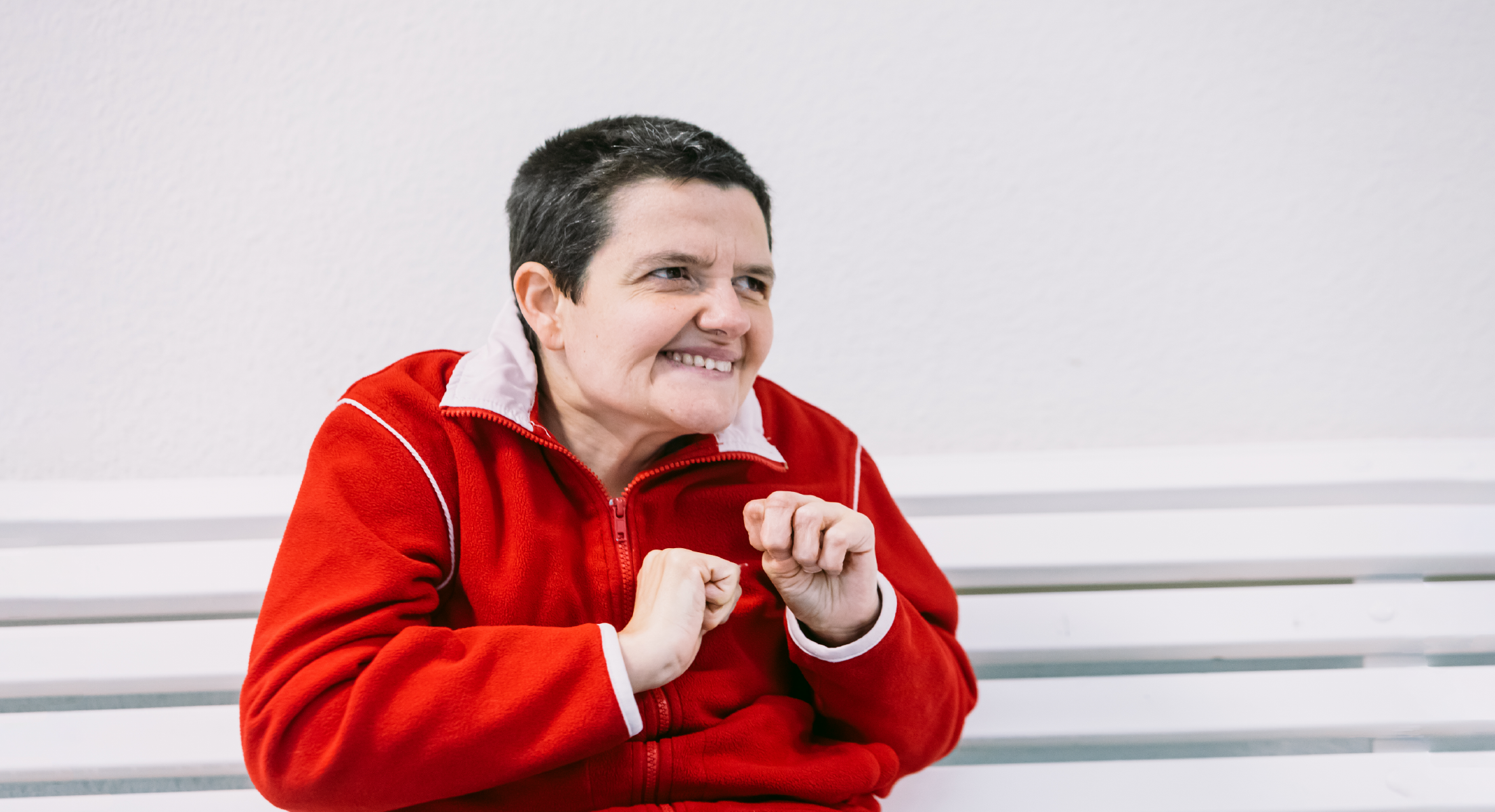 Mujer autista sentada en un banco sonriendo.