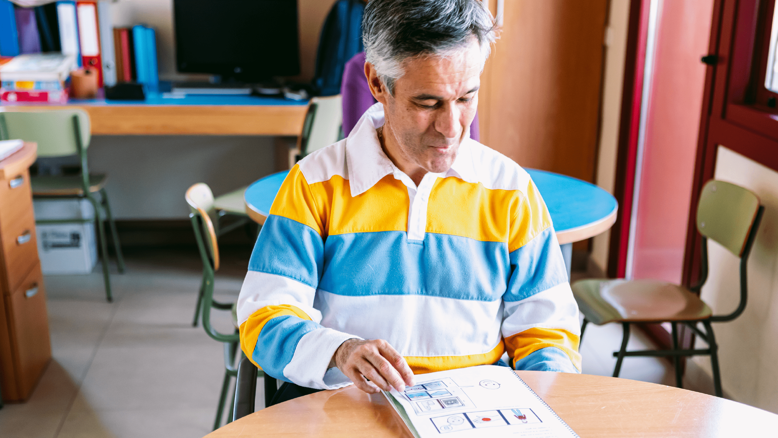 Hombre sentado en un aula leyendo un cuaderno