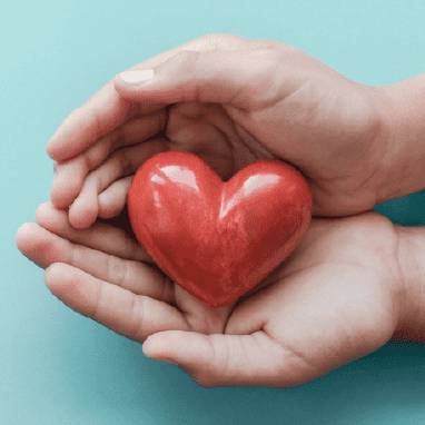 Miniatura de dos manos sujetando una piedra roja en forma de corazón