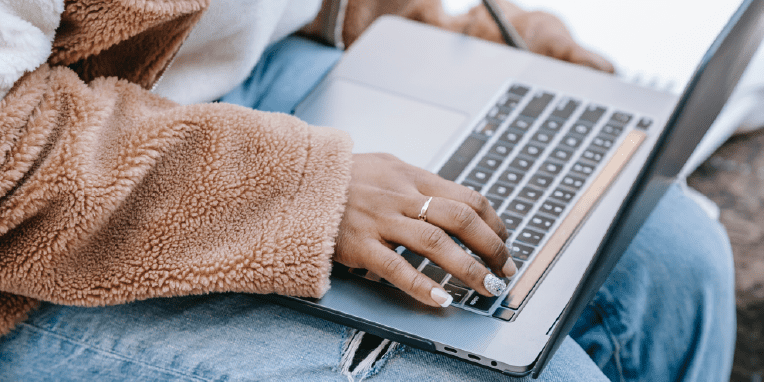 Miniatura de una mano de mujer encima de un teclado de un ordenador portátil