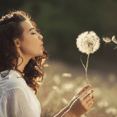 Mujer soplando un diente de león.