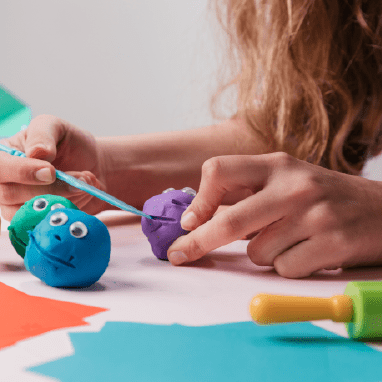 Manos dándole forma a plastilina de colores.
