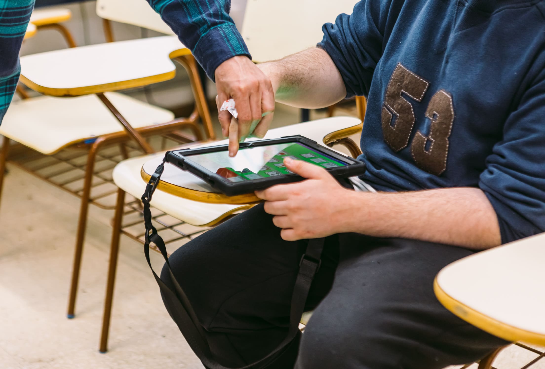 Mano de un hombre tocando la pantalla de una tablet con la ayuda de la mano de otro hombre