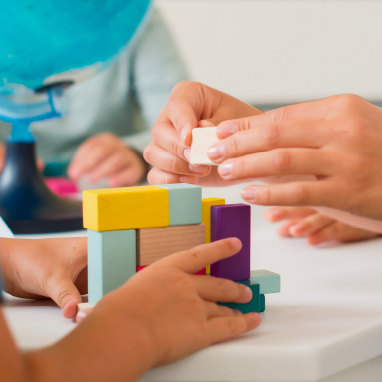 Manos formando una figura con bloques de madera de colores