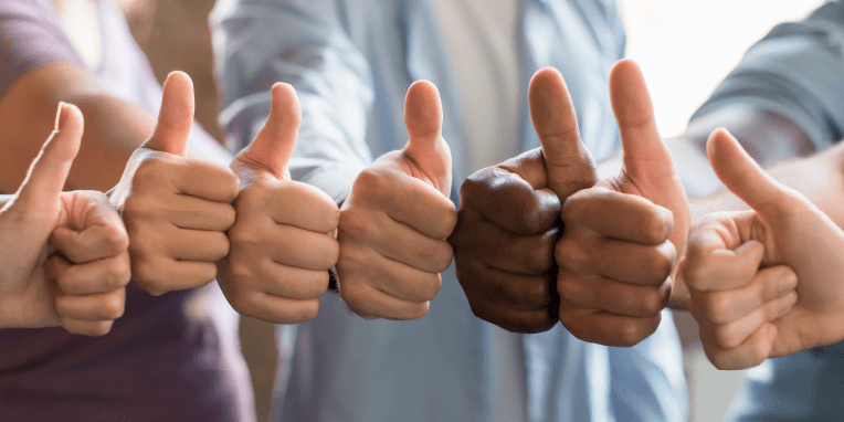 Varias manos juntas con el pulgar levantado hacia arriba
