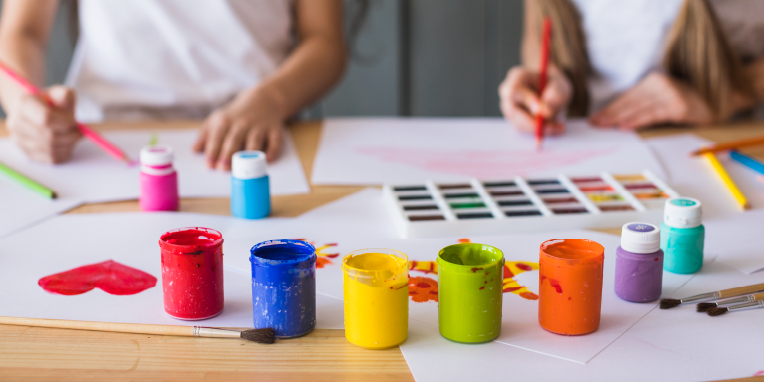 Manos trabajando con acuarelas y pinturas de varios colores