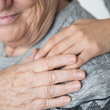 Mano adulta acariciando mano jovén sobre su hombro.