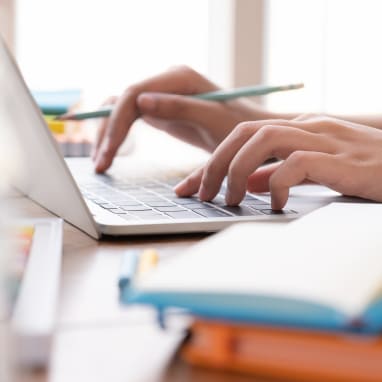 Imagen de dos manos utilizando el teclado de un portatil.