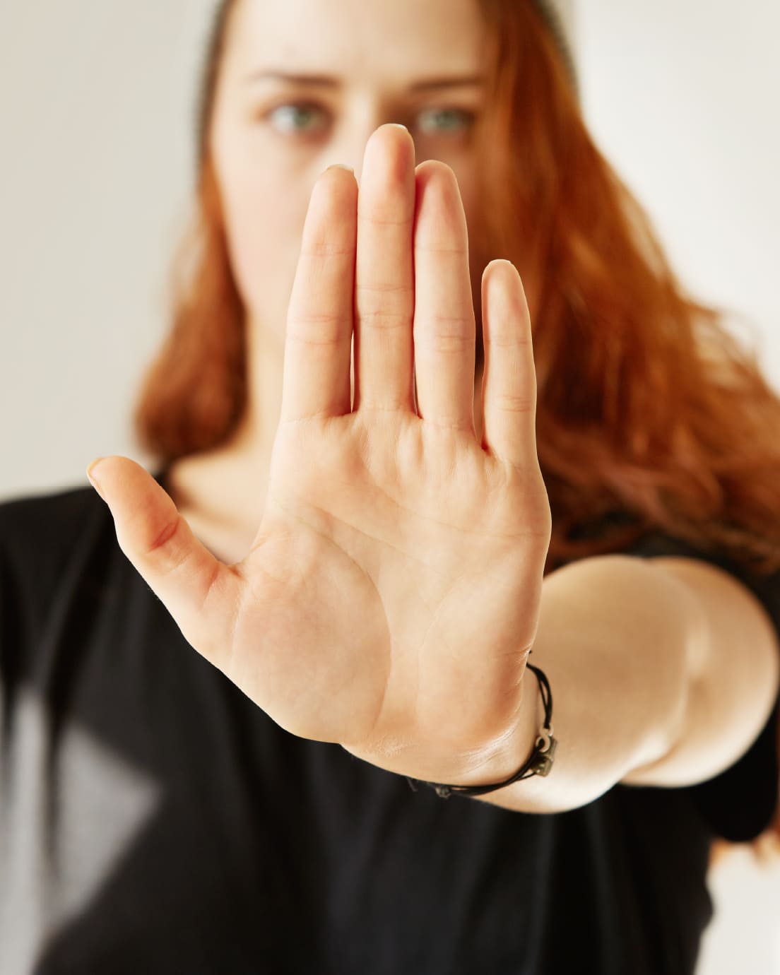 Mano de una mujer frente a cámara haciendo señal de parar.