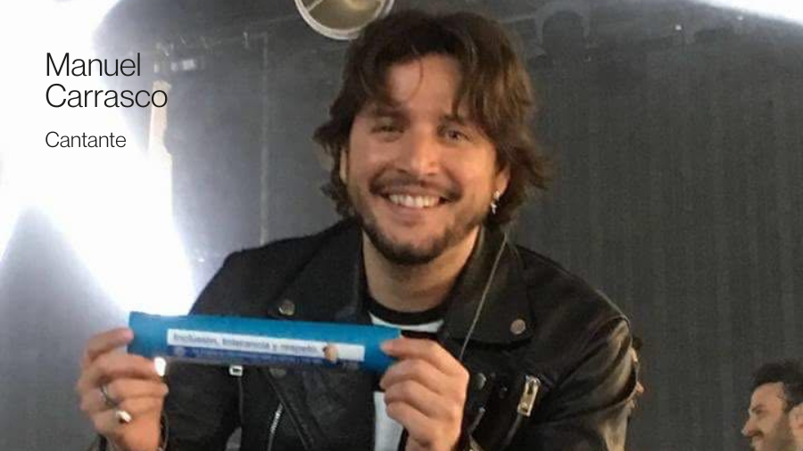El cantante Manuel Carrasco sonriendo a cámara con un testigo azul en la mano