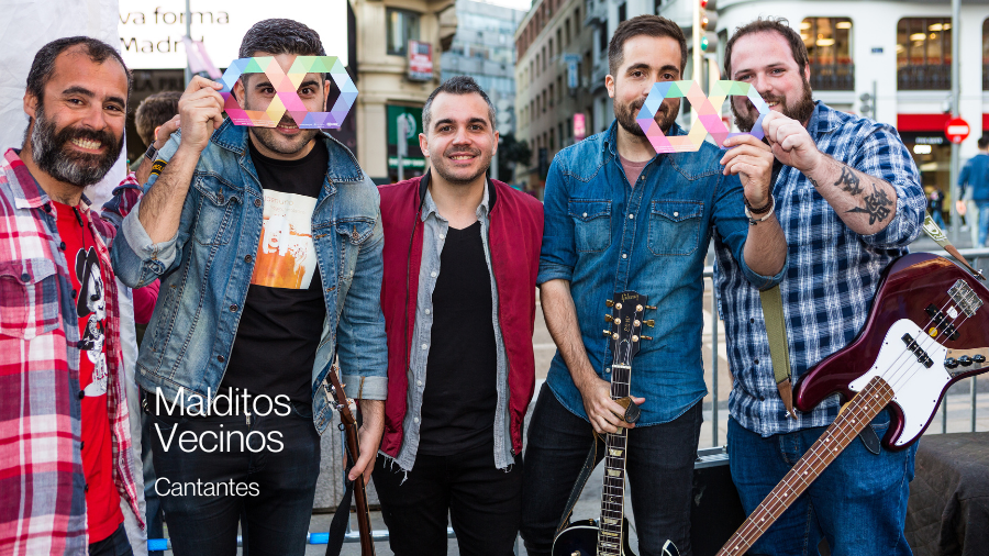 El grupo de música Malditos Vecinos posando con un infinito multicolor y mirando a cámara