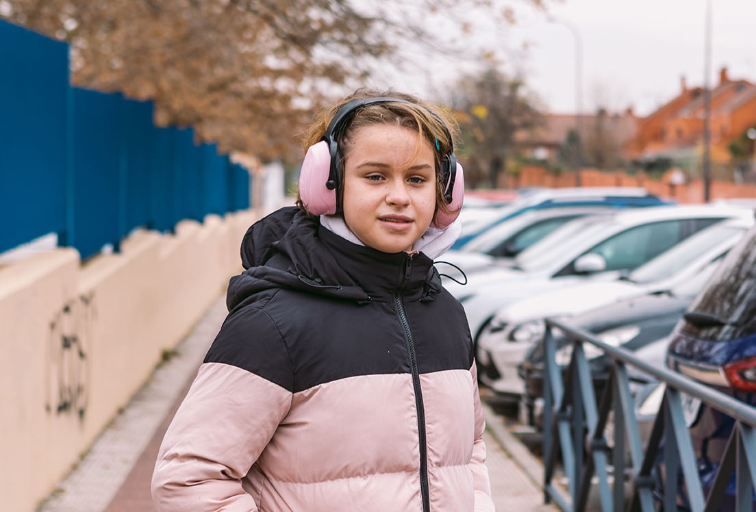 Niña con cascos antirruido sonriendo mirando a cámara