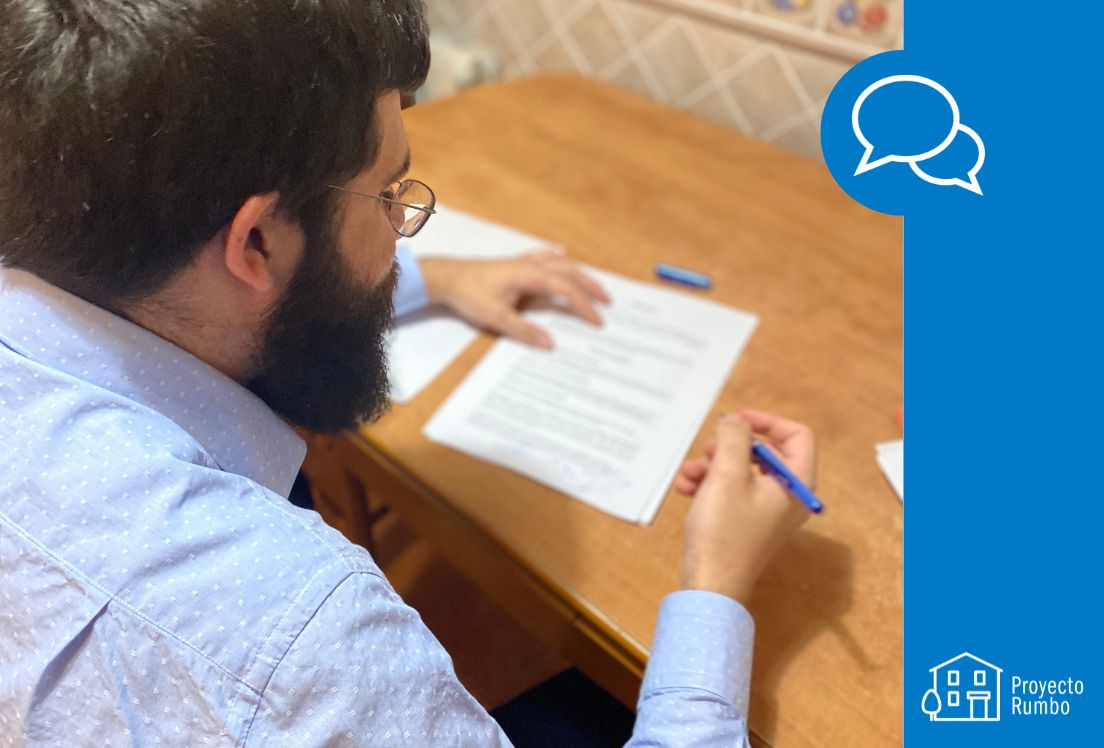 Fotografía del protagonista de esta historia de vida, Samuel. Un hombre con autismo de 35 años que vemos de lado, sentado a una mesa, mientras se dispone a firmar o escribir en un papel.