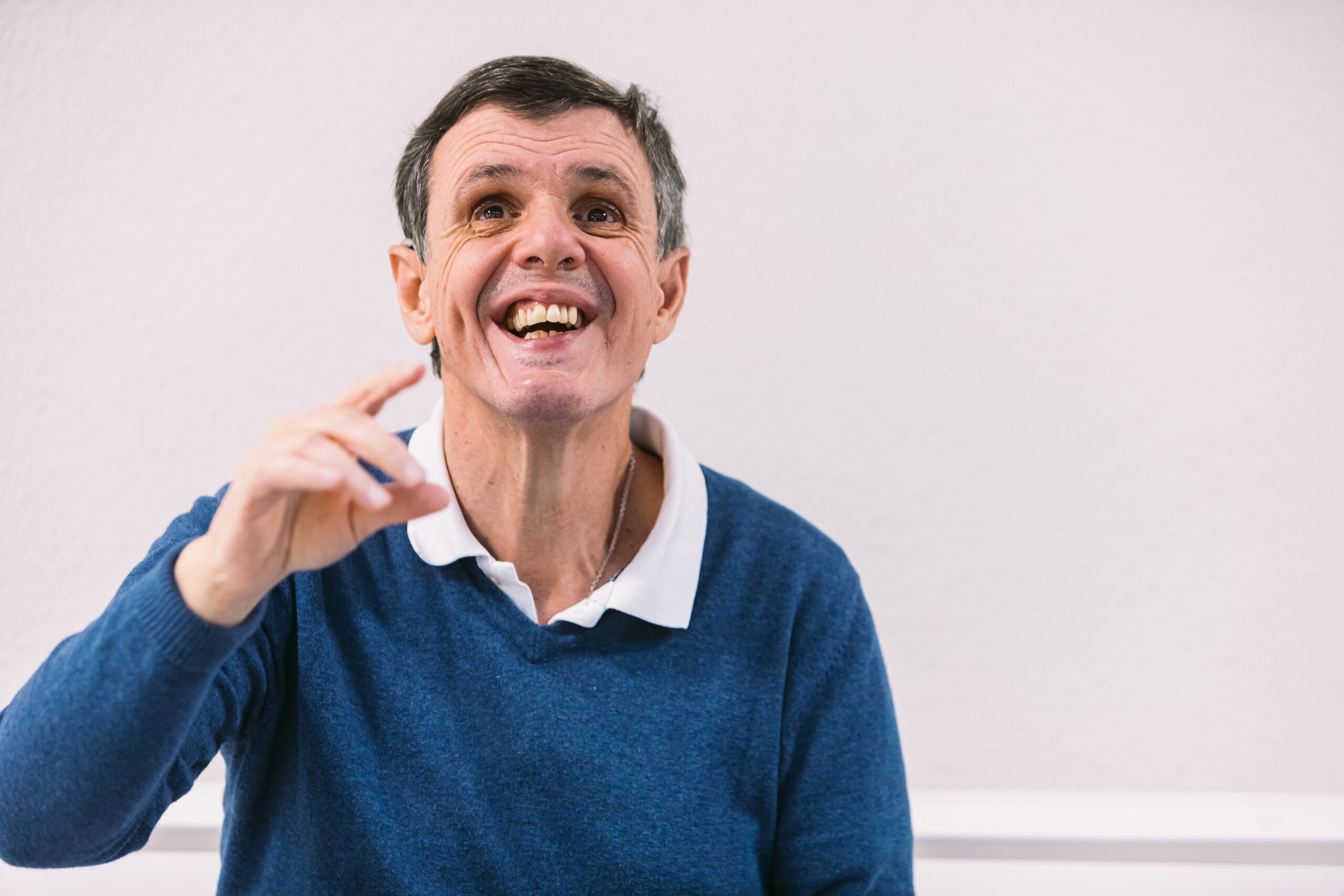 Un hombre adulto con autismo sonríe mirando hacia arriba.