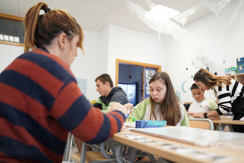Una profesora de educación especial ayudando a una niña con autismo en una clase