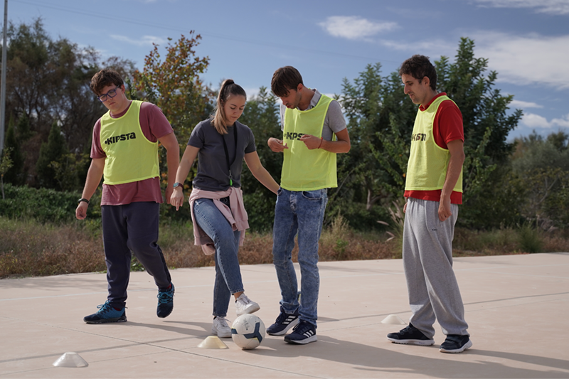 Tres personas con autismo junto con una persona de apoyo jugando al fútbol