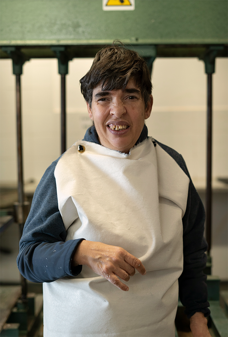 Mujer con autismo sonriendo mirando a la cámara con un delantal blanco