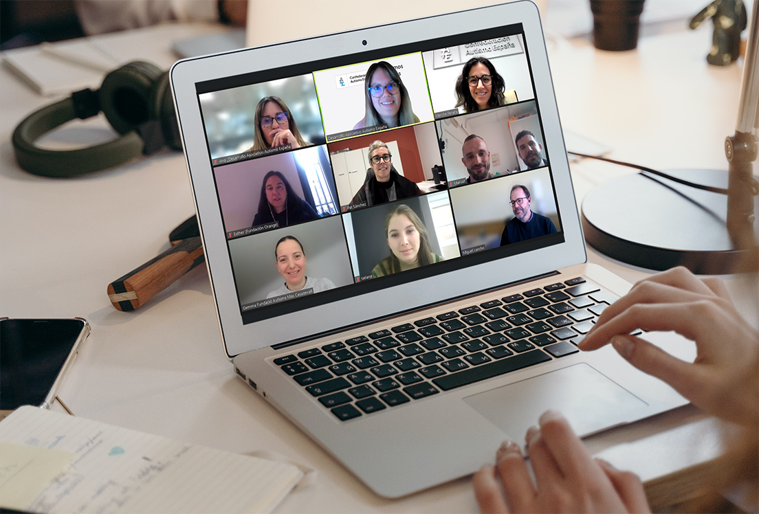 Unas manos frente a un ordenador portátil en el que se ve una reunión online con 9 personas