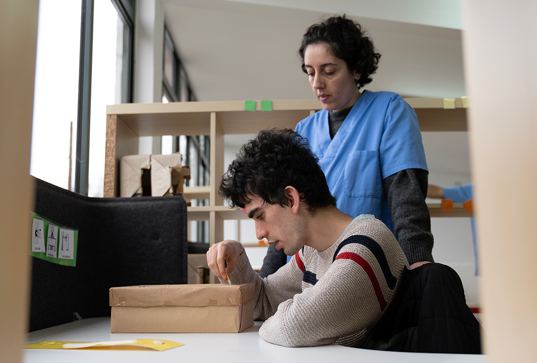 Un chico autista con su persona de apoyo en un aula