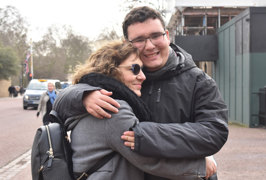 Un chico autista abrazando a su madre y sonriendo a la cámara