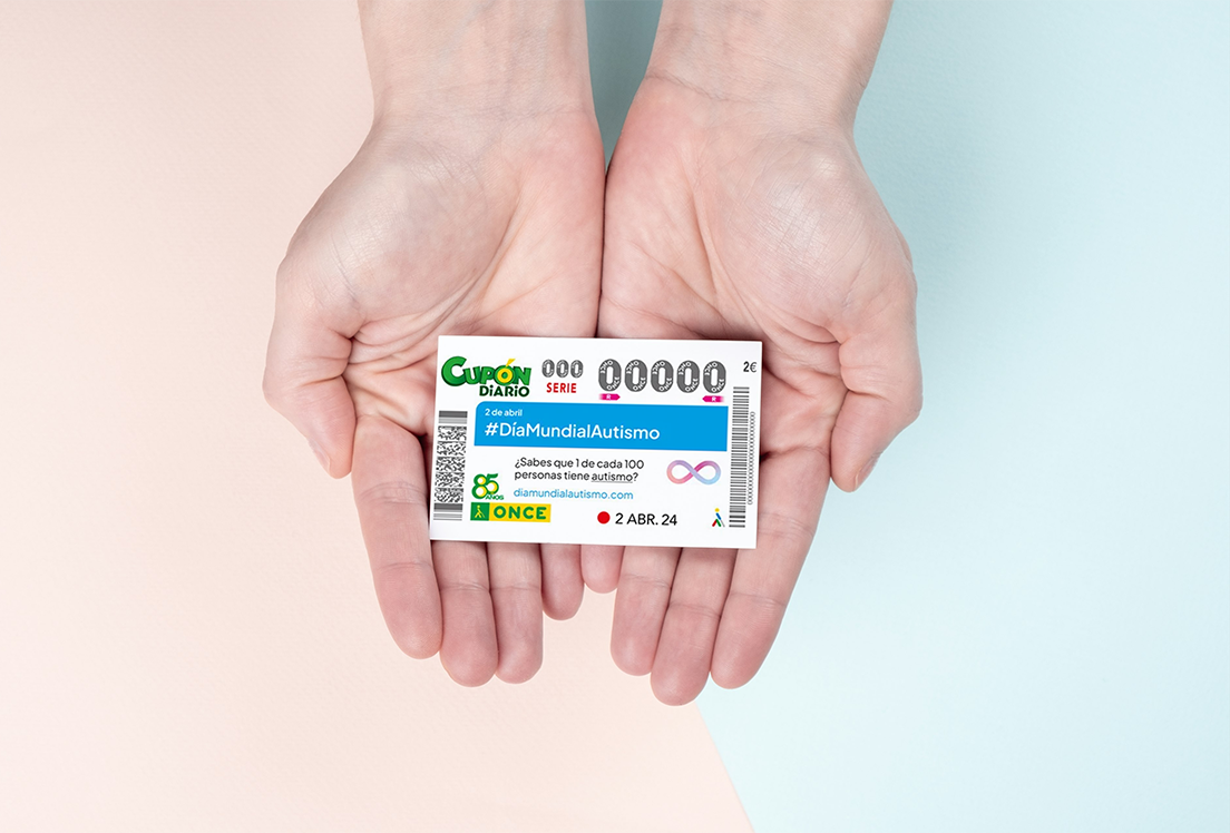 Unas manos sujetando el cupón diario de la ONCE dedicado al Día Mundial del Autismo
