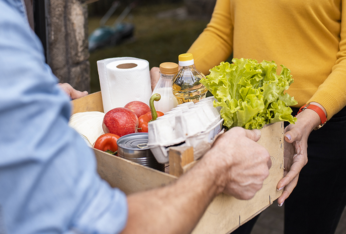 Una persona entregándole una cesta de productos básicos a otra