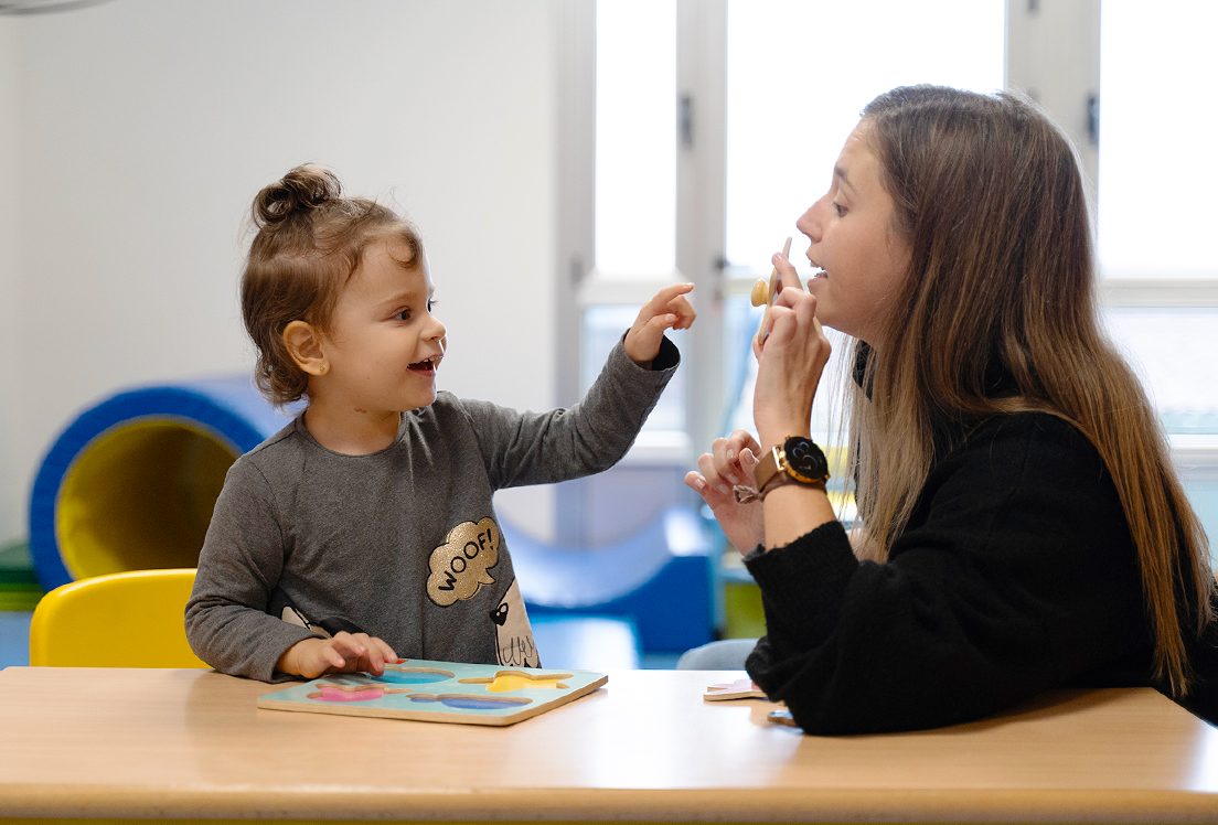 Una niña con autismo junto a una profesional de atención temprana haciendo un juego
