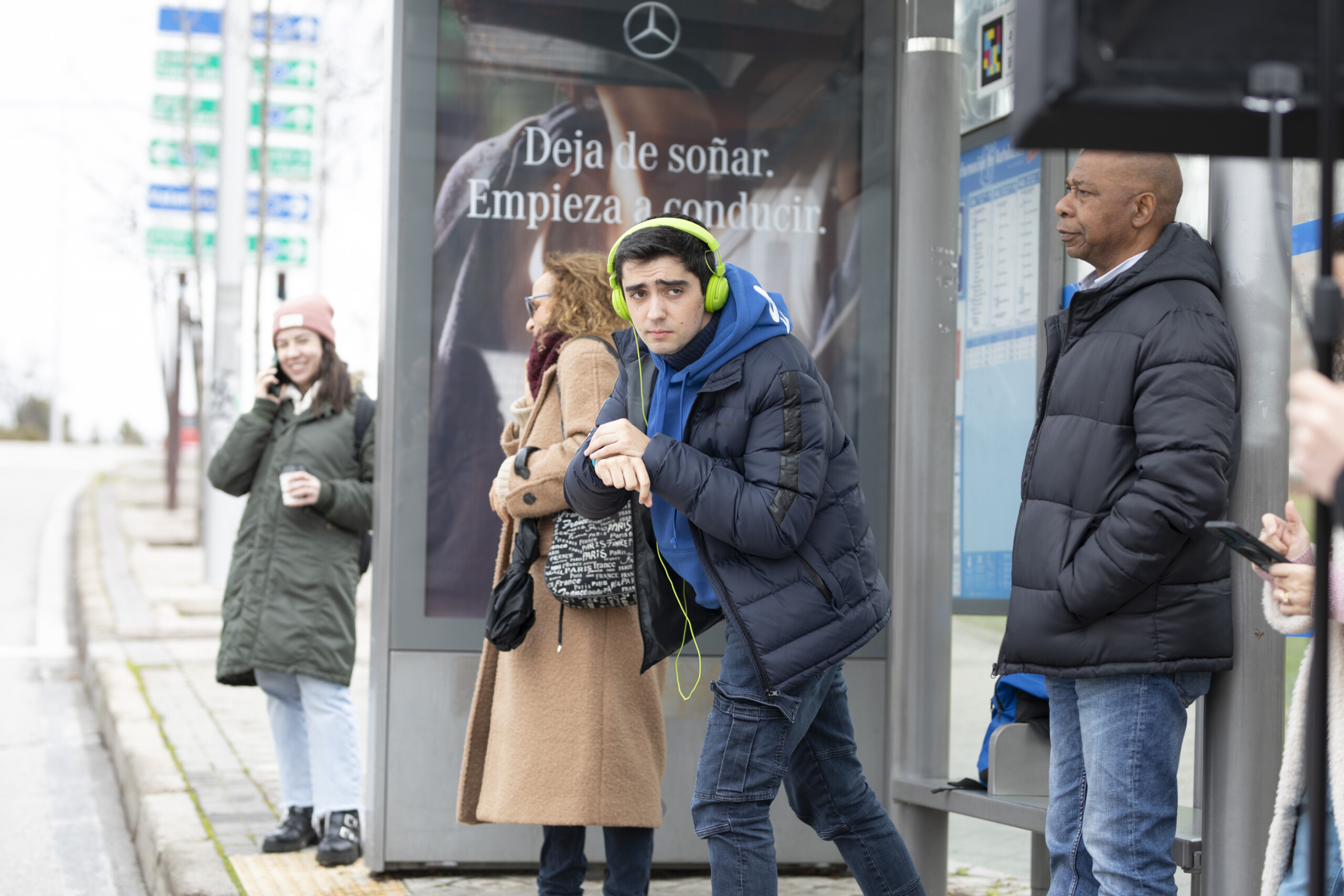 Joven con cascos esperando en la parada del autobus