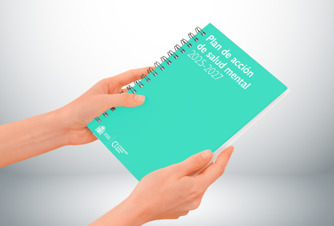Dos manos sujetando un cuaderno con la portada del PLan de Salud mental