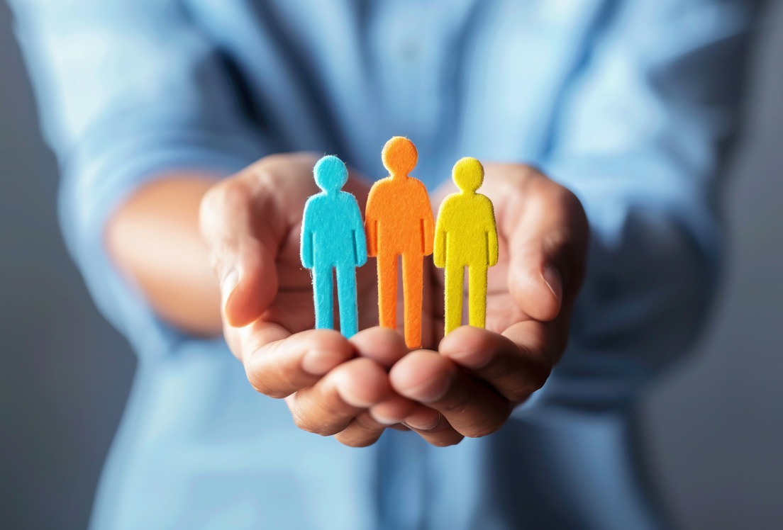 Unas manos sujetando tres figuras de personas.