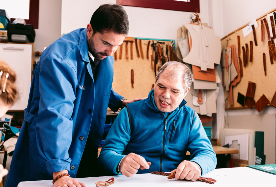persona sentada en un taller de cuero junto a su tutor de pie